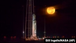 The Orbital ATK Antares rocket, with the Cygnus spacecraft onboard, sits on launch Pad-0A as the moon sets, Saturday, Oct. 15, 2016 at NASA's Wallops Flight Facility in Virginia.