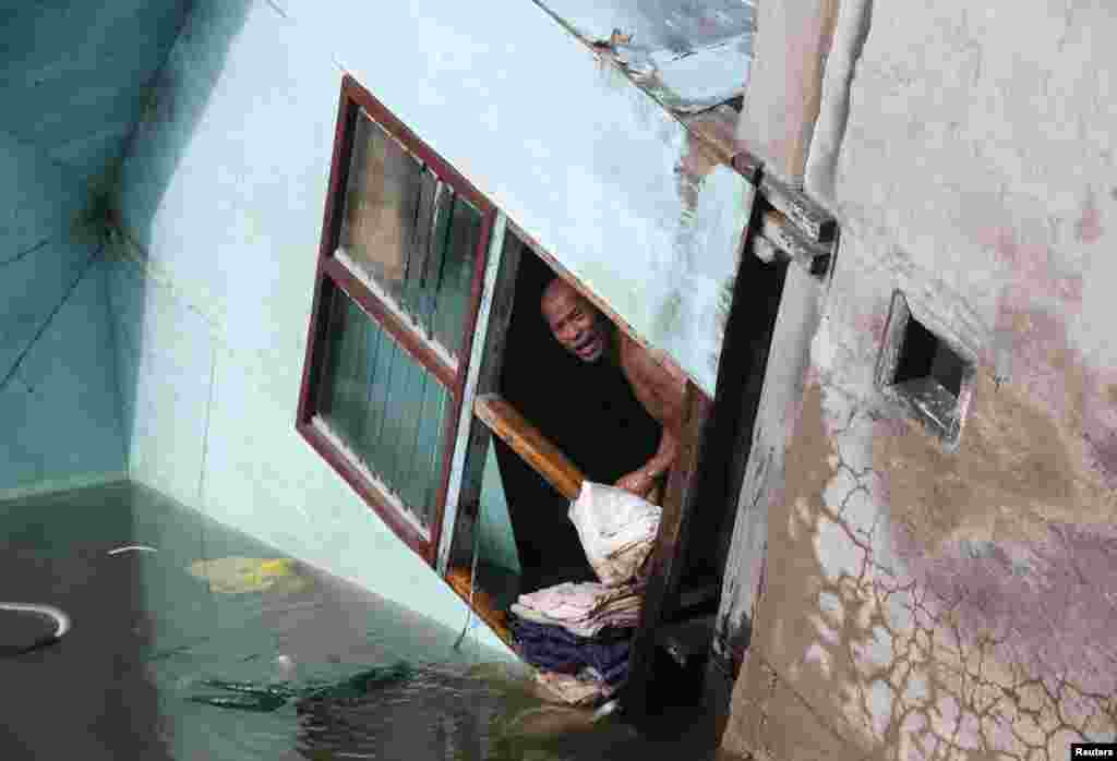 Seorang warga melihat keluar dari jendela rumah keluarganya, yang separuh jendelanya jatuh ke sungai Buenavista, di kota Bohol sehari setelah gempa bumi melanda Filipina tengah.