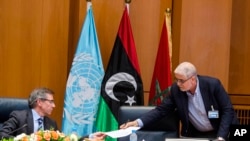 FILE - Bernardino Leon, left, the U.N. special envoy to Libya, receives a document from Mustafa Abushagur, a representative of the internationally recognized government that fled to Tobruk, Libya, during a meeting in Skhirate, Morocco, July 2, 2015.