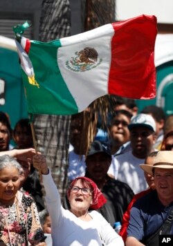 A woman waves a Mexican flag prior to a speech by Mexican President Andres Manuel Lopez Obrador at a rally in Tijuana, Mexico, June 8, 2019.