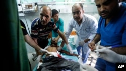 Nhân viên cấp cứu Palestine chăm sóc cho một trẻ em bị thương trong vụ oanh kích của Israel