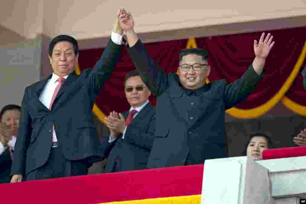 North Korean leader Kim Jong Un, right, raises hands with China's third highest ranking official, Li Zhanshu, during a parade for the 70th anniversary of North Korea's founding day in Pyongyang, North Korea, Sept. 9, 2018. 