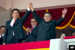 김정은 국무위원장(오른쪽)이 리잔수 중국 전국인민대표회의 상무위원장과 손을 들며 인사하고 있다.