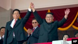 North Korean leader Kim Jong Un, right, raises hands with China's third highest ranking official, Li Zhanshu, during a parade for the 70th anniversary of North Korea's founding day in Pyongyang, North Korea, Sept. 9, 2018. 