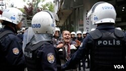 FILE - A woman argues with riot police as they detain protesters during a demonstration against the arrest of Nuriye Gulmen and Semih Ozakca, who are on hunger strike protest, in Ankara, Turkey, May 22, 2017.
