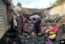 Warga memeriksa puing-puing pasca kebakaran di pasar darurat di dekat kamp pengungsi Rohingya di Kutupalong, Bangladesh, Jumat, 2 April 2021.