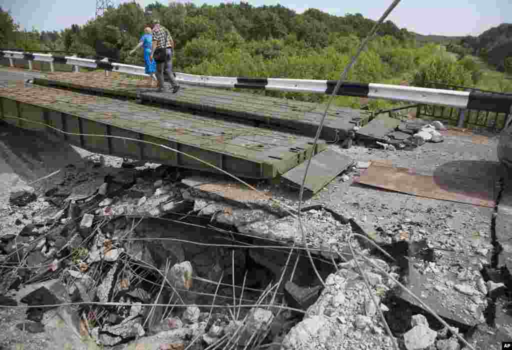 People walk across a heavily damaged bridge near the village of Debaltseve, Donetsk region, July 31, 2014.