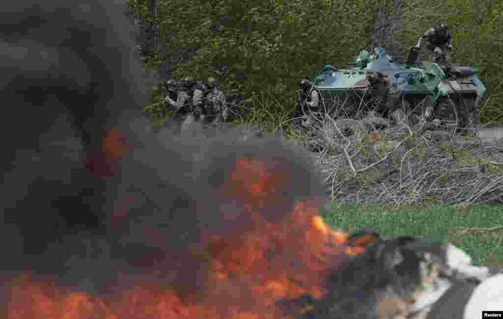 Ukrainian security force officers are deployed at a checkpoint set on fire and left by pro-Russian separatists near Slovyansk, April 24, 2014. 