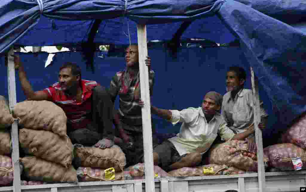 Indian laborers watch an election rally of the Congress party in Mumbai.