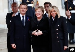 German Chancellor Angela Merkel, center, is greeted by French President Emmanuel Macron and his wife Brigitte Macron as she arrives at the Elysee Palace in Paris to participate in a World War I Commemoration Ceremony, Nov. 11, 2018.