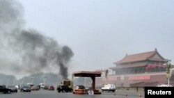 FILE - Vehicles travel along Chang'an Avenue as smoke raises in front of a portrait of late Chinese Chairman Mao Zedong at Tiananmen Square in Beijing, Oct. 28, 2013.