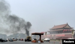 Vehicles travel along Chang'an Avenue as smoke raises in front of a portrait of late Chinese Chairman Mao Zedong at Tiananmen Square in Beijing, Oct. 28, 2013.