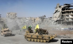 Syrian Democratic Forces (SDF) fighters ride atop of military vehicles as they celebrate victory in Raqqa, Syria, Oct. 17, 2017.