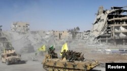 Syrian Democratic Forces (SDF) fighters ride atop of military vehicles as they celebrate victory in Raqqa, Syria, Oct. 17, 2017. 