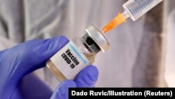 USA, Washington, FILE PHOTO: A woman holds a small bottle labeled with a "Vaccine COVID-19" sticker