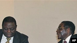 Zimbabwean President Robert Mugabe, right, chats to Prime Minister Morgan Tsavangirai during their end of year press conference at State House in Harare, saying they were dispelling rumors of disunity in the Government of National Unity, Dec. 20, 2010
