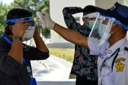 Seorang petugas keamanan yang mengenakan pelindung wajah memeriksa suhu pengunjung di tengah kekhawatiran terhadap COVID-19, sebelum ujian masuk perguruan tinggi di Banda Aceh pada 5 Juli 2020. (Foto: AFP/Chaideer Mahyuddin)