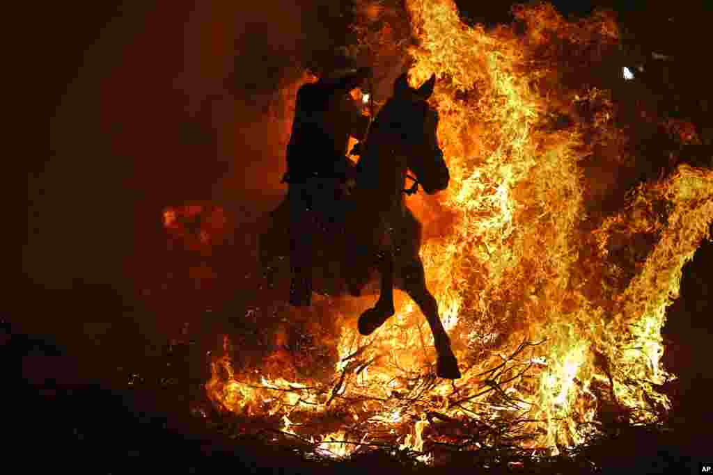 A man rides a horse through a bonfire as part of a ritual in honor of Saint Anthony the Abbot, the patron saint of domestic animals, in San Bartolome de Pinares, Spain, Jan. 16, 2016.