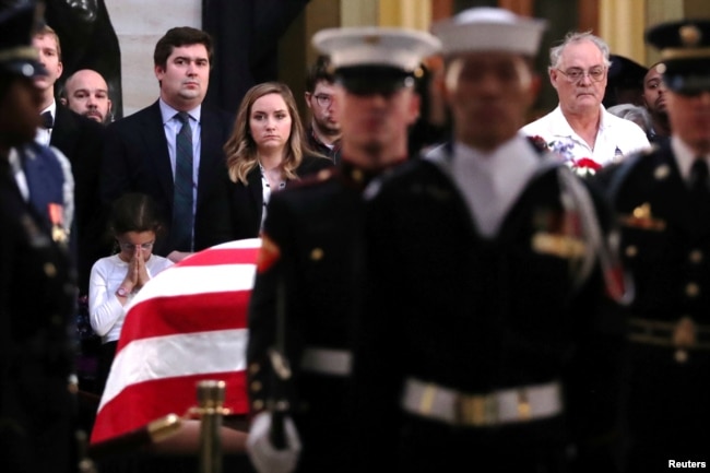 A girl prays as mourners watch the changing of the military guard as they pay their respects to former U.S. President George H. W. Bush as his body lies in state in the Rotunda at the U.S. Capitol in Washington, U.S., Dec. 4, 2018.