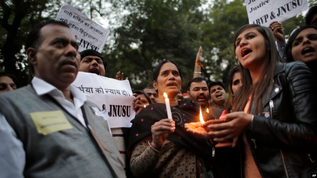 The father, left and mother, center, of the Indian student victim who was fatally gang raped on this day three years ago on a moving bus in the Indian capital, join others at a candle lit vigil in New Delhi, India, Dec. 16, 2015. 