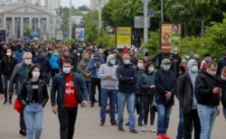 FILE - Opposition supporters wearing protective face masks wait in a line to put signatures in support of their potential candidates in the upcoming presidential election in Minsk, Belarus, May 31, 2020.