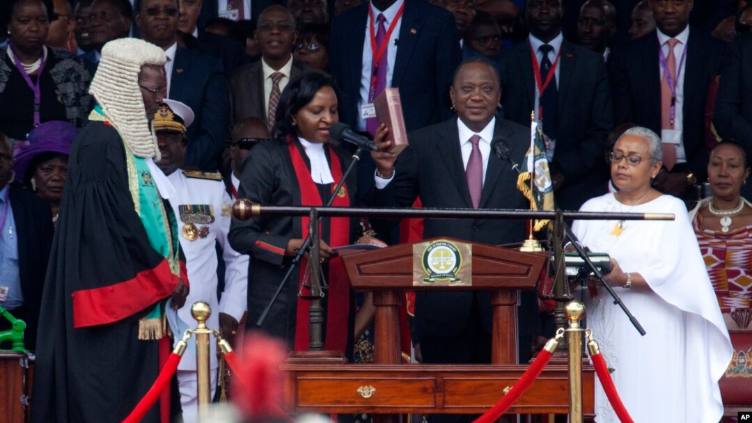 Kenyan President Uhuru Kenyatta, center, is sworn in as his wife, Margaret, right, looks on during his inauguration at Kasarani Stadium in Nairobi, Kenya, Nov. 28, 2017. 