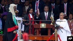 Kenyan President Uhuru Kenyatta, center, is sworn in as his wife, Margaret, right, looks on during his inauguration at Kasarani Stadium in Nairobi, Kenya, Nov. 28, 2017. 