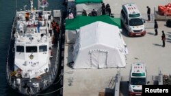 Sebuah ambulans membawa jenazah penumpang kapal tenggelam di pelabuhan Jindo, Korea Selatan (23/4). (Reuters/Issei Kato)