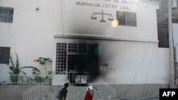 People walk by and look at the tribunal set on fire the previous day by armed gangs, in Port-au-Prince, Haiti, March 6, 2024.