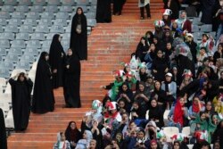 Iranian women follow the 2022 World Cup qualifier soccer match between Iran and Cambodia as female police officers stand, left, at the Azadi (Freedom) Stadium in Tehran, Iran, Oct. 10, 2019.
