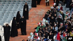Iranian women follow the 2022 World Cup qualifier soccer match between Iran and Cambodia as female police officers stand, left, at the Azadi (Freedom) Stadium in Tehran, Iran, Oct. 10, 2019.