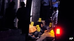 FILE - Police investigators stand over the bodies of six men who were killed in Tegucigalpa, Honduras, Sept. 14, 2016. 