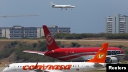 FILE - Airplanes wait their turn to take off on a runway of the Simon Bolivar airport in La Guaira, outside Caracas, Sept. 23, 2013.