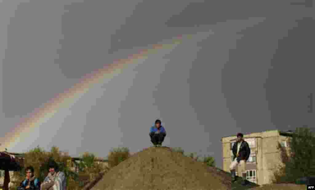 A rainbow appears in the sky, as Afghan men stand on a roadside in Kabul, Afghanistan, Friday, Oct. 21, 2011. (AP Photo/Muhammed Muheisen)