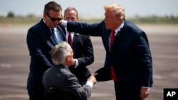 President Donald Trump talks with Sen. Ted Cruz, R-Texas, left, and Gov. Greg Abbott, R-Texas, after arriving at Ellington Field Joint Reserve Base, May 31, 2018, in Houston. 