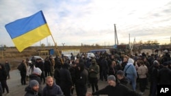 FILE - Ukrainian army veterans and volunteers wave the national flag at a checkpoint near the town of Zolote, Luhansk region, Ukraine, Oct. 9, 2019.