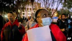 Seorang perempuan memegang lilin dalam acara doa bersama di luar gedung Pengadilan Glynn County di Georgia, AS, saat persidangan kasus pembunuhan Ahmaud Arbery berlangsung pada 22 November 2021. (Foto: AP/Stephen B. Morton)