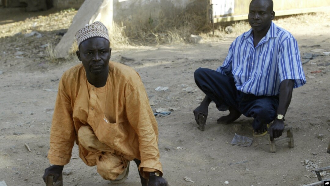 Polio sufferers Yusuf Umar, right, and Aminu Ahmed use wooden blocks to propel themselves through the dusty streets of Kano, Nigeria, November 28, 2008. 