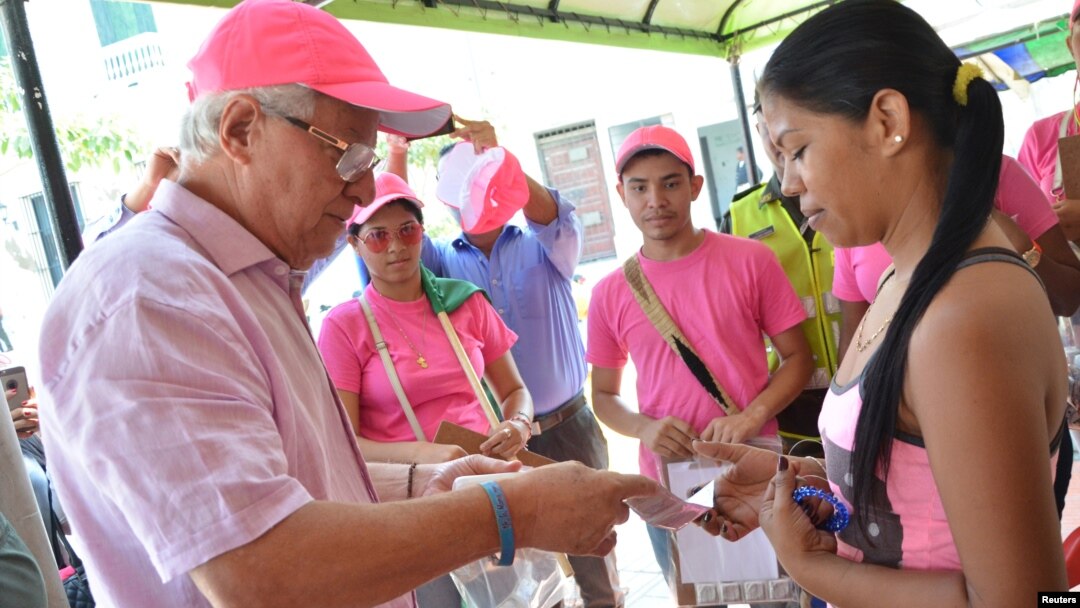 Soledad's Mayor Joao Herrera (L) gives a woman, condoms and kits with insect repellent during a campaign to fight the spread of Zika virus in Soledad municipality near Barranquilla, Colombia, in this Feb. 1, 2016 handout photo supplied by the Soledad Mun