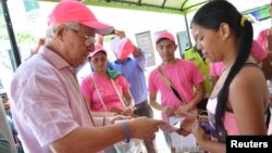 Soledad's Mayor Joao Herrera (L) gives a woman, condoms and kits with insect repellent during a campaign to fight the spread of Zika virus in Soledad municipality near Barranquilla, Colombia, in this Feb. 1, 2016 handout photo supplied by the Soledad Mun