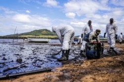 People scoop leaked oil from the vessel MV Wakashio, belonging to a Japanese company but Panamanian-flagged, that ran aground and caused oil leakage near Blue bay Marine Park in southeast Mauritius, Aug. 9, 2020.