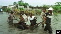 Une famille transportée dans un chariot en pleine inondation à Kinshasa, 31 mars 1997.