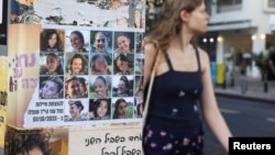 (FILE) A woman makes her way past images of those taken hostage or killed during the deadly October 7 attack in Tel Aviv, Israel September 16, 2024.