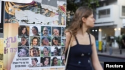 La gente pasa entre imágenes de los rehenes o asesinados durante el mortal ataque del 7 de octubre en Tel Aviv. REUTERS