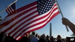 Anggota Marinir AS Terri Shreiner mengibarkan bendera AS dalam pawai di Washington Memorial, menuntut penghentian penutupan sebagian kegiatan pemerintah, di Washington, 15 Oktober 2013.