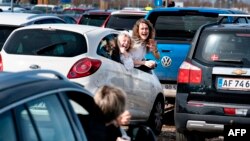 Jóvenes reaccionan durante un servicio de Pascuas en autos en un estacionamiento del Aeropuerto Aalborg, en Dinamarca, el 12 de abril de 2020. 