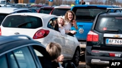 Young people react during the drive-in Easter service at the parking lot at Aalborg Airport, Denmark, April 12, 2020, amid the spread of the novel coronavirus COVID-19.