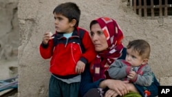 FILE - Members of a Syrian Kurdish refugee family from Kobani sit in the village of Alanyurt on the Turkish side of the Turkey-Syria border.