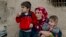 FILE - Members of a Syrian Kurdish refugee family from Kobani sit in the village of Alanyurt on the Turkish side of the Turkey-Syria border.