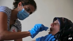 FILE - A member of the International Red Cross takes a saliva sample from a woman whose sister went missing in 1976 during the Lebanese civil war, at her home, in a southern suburb of Beirut, Lebanon, July 11, 2016.